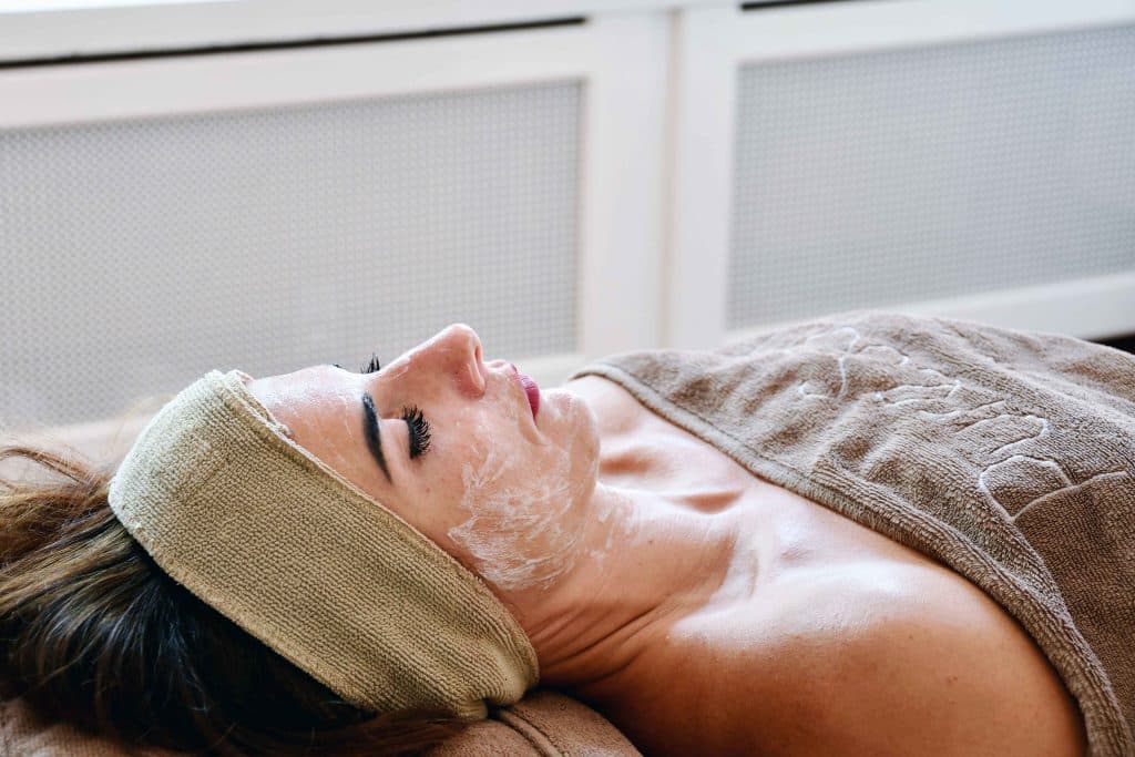 Cliënte ligt ontspannen met een masker tijdens een gezichtsbehandeling