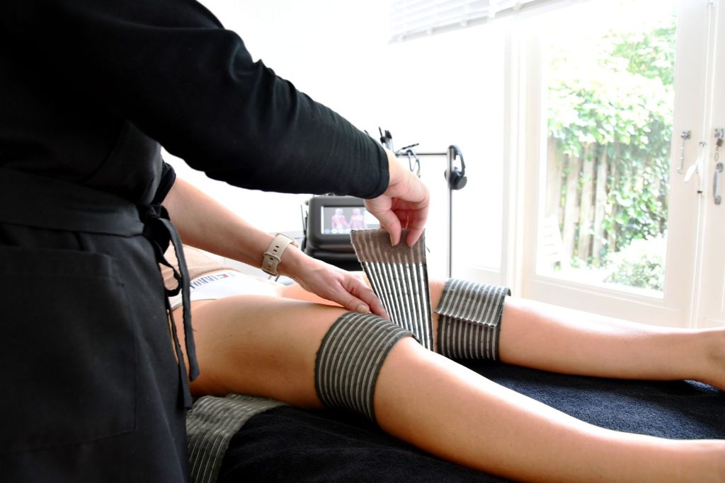 Vibra-Beauty bij PureSan: de behandelbanden worden om de benen van een cliënte gelegd