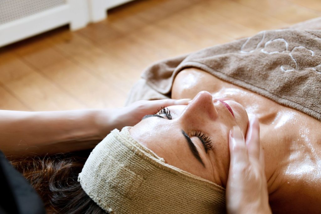 Ontspannende gezichtsmassage bij een cliënte met een haarband